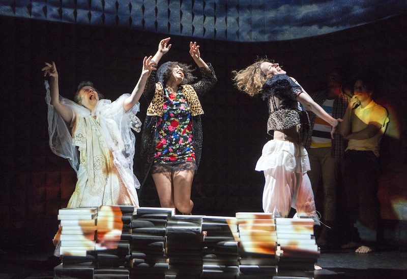 Three women dance gleefully with cackling grins on their faces